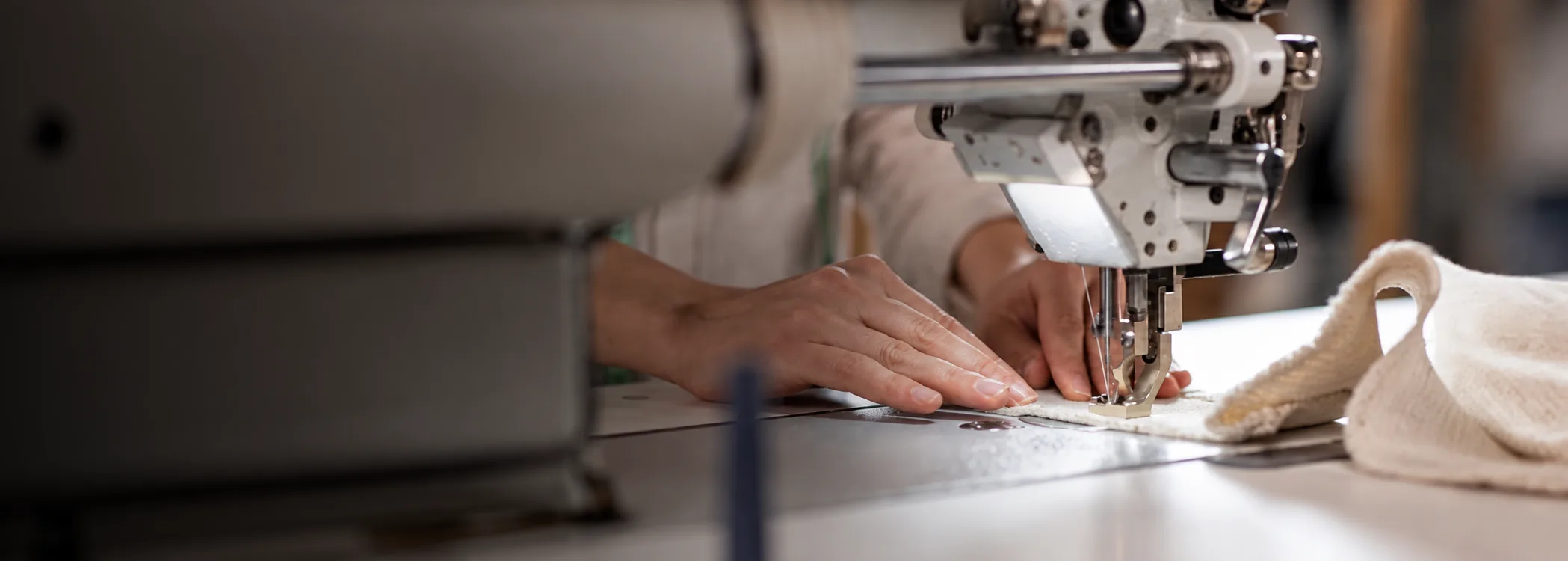 A machinist stitching a hem on an industrial sewing machine
