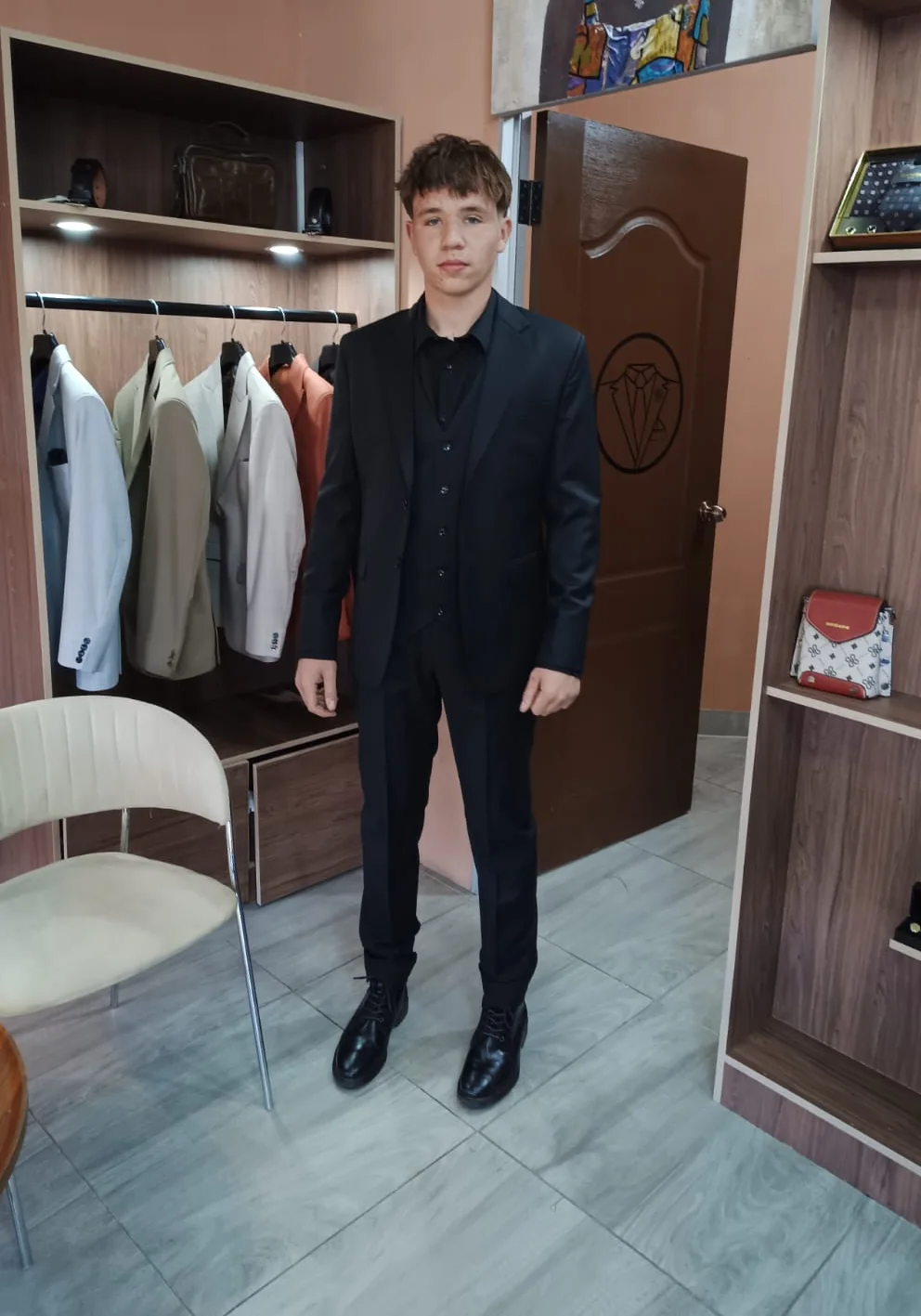 A young Flux client in a black three-piece bespoke suit, photographed in the branch